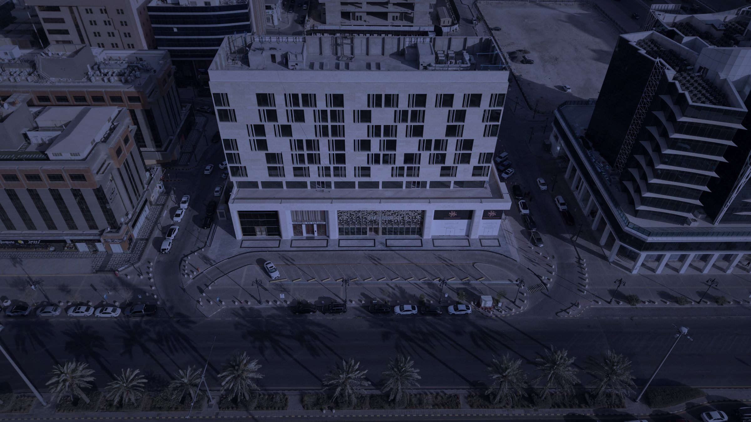 Top-down drone photograph of the tower and its palm-lined frontage at night, between Tahlia Street and the surrounding Al-Olaya blocks.